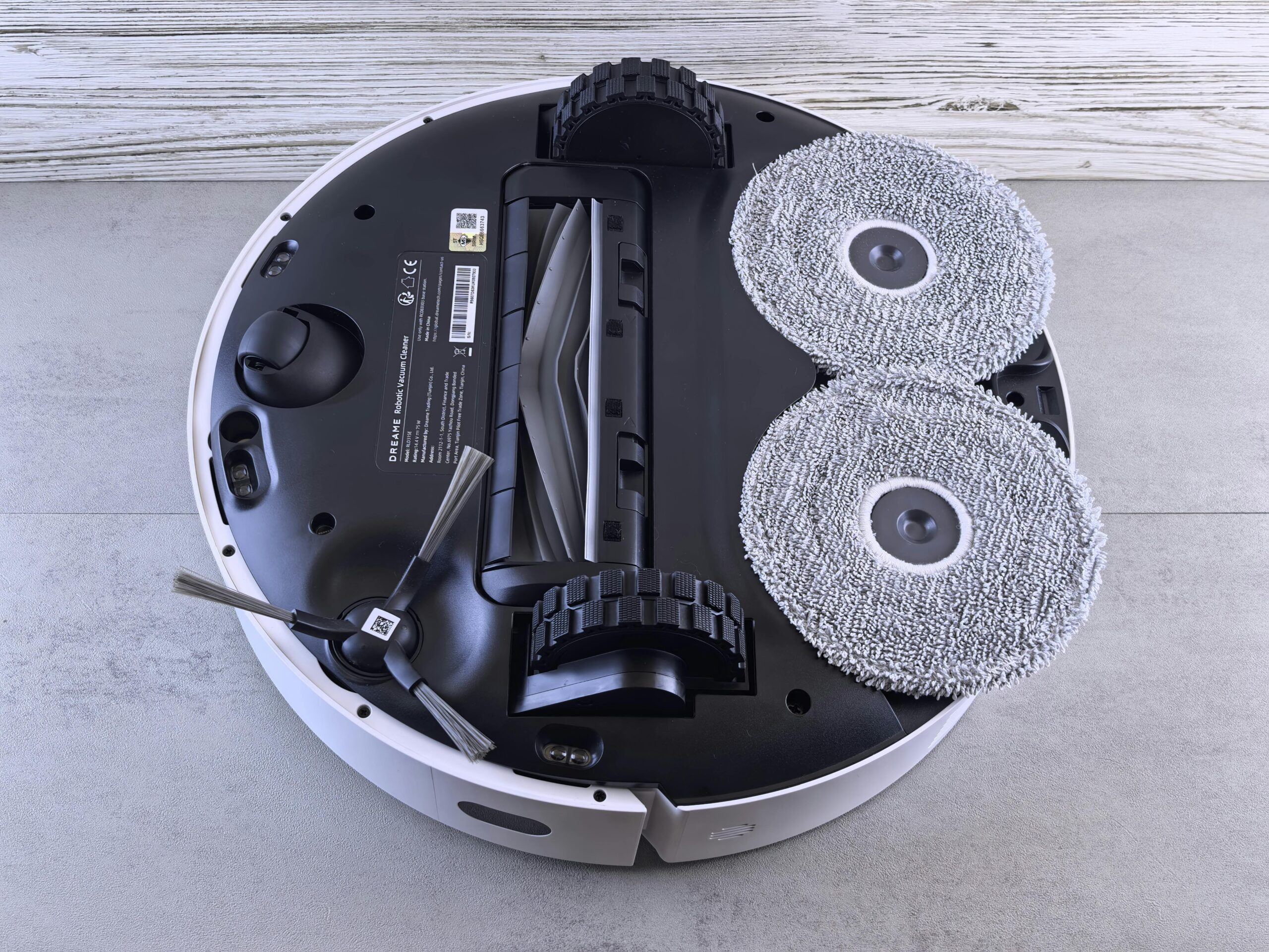 Detailed view of a robotic vacuum cleaner's underside showing brushes and wheels.